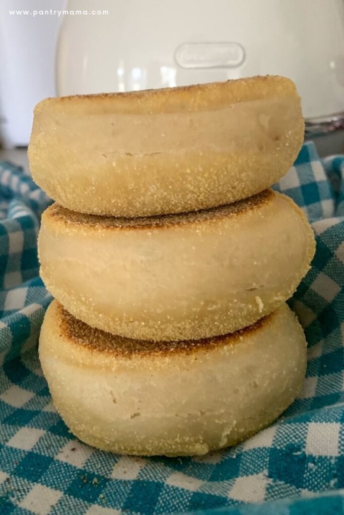 Stack of three Sourdough English Muffins on a blue and white dish towel.