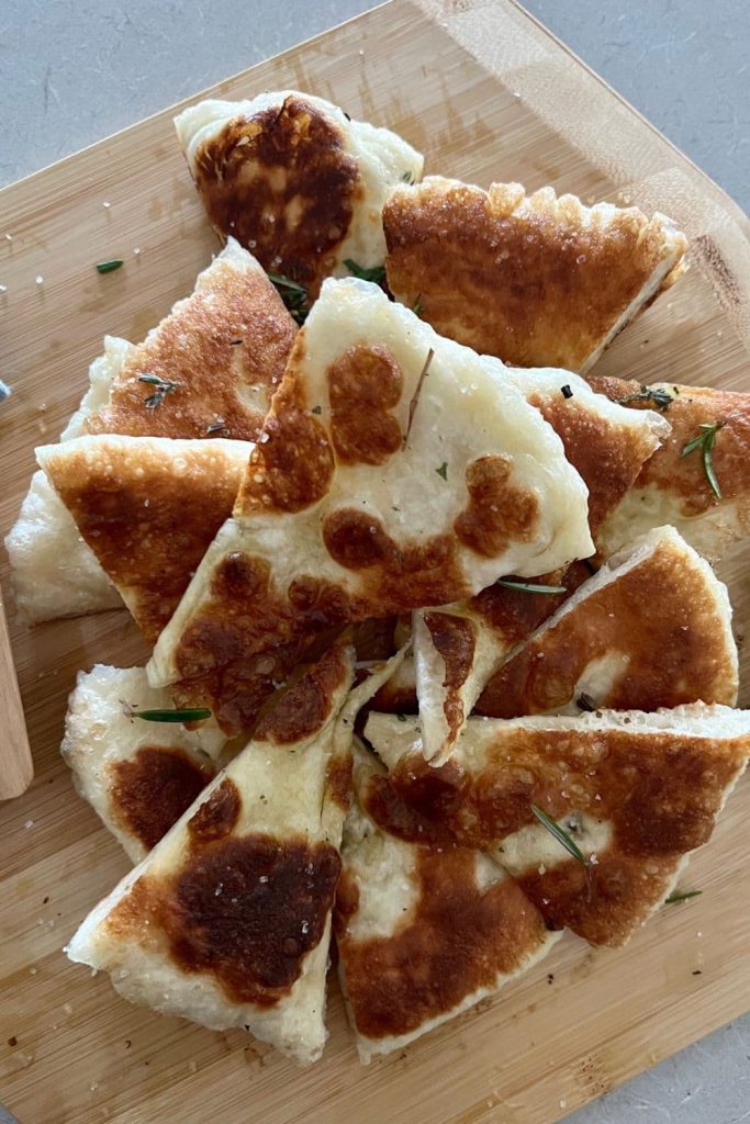 Pieces of fried sourdough pizza dough arranged on a wooden pizza board.
