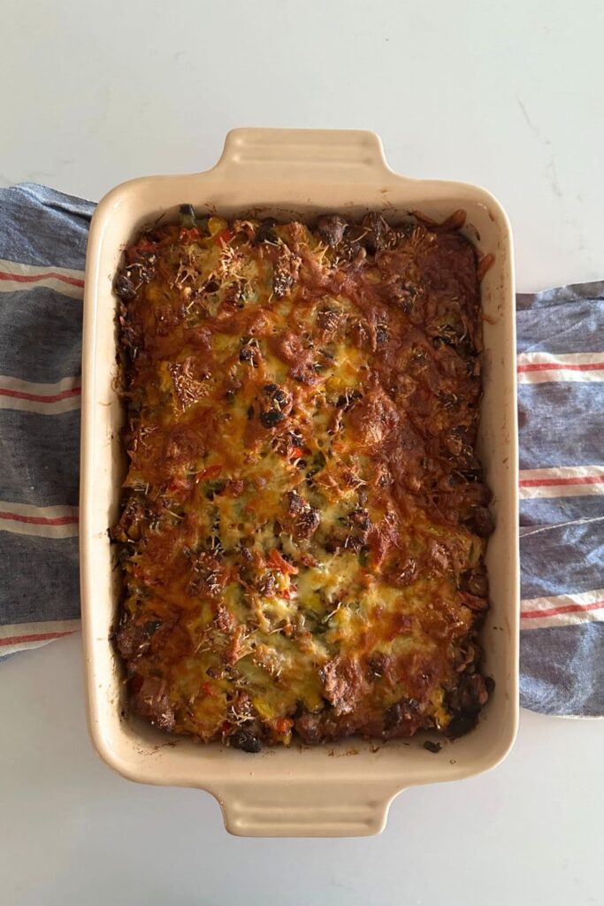 A baking dish containing baked sourdough breakfast casserole. There is a red, white and blue dish towel underneath the baking dish.