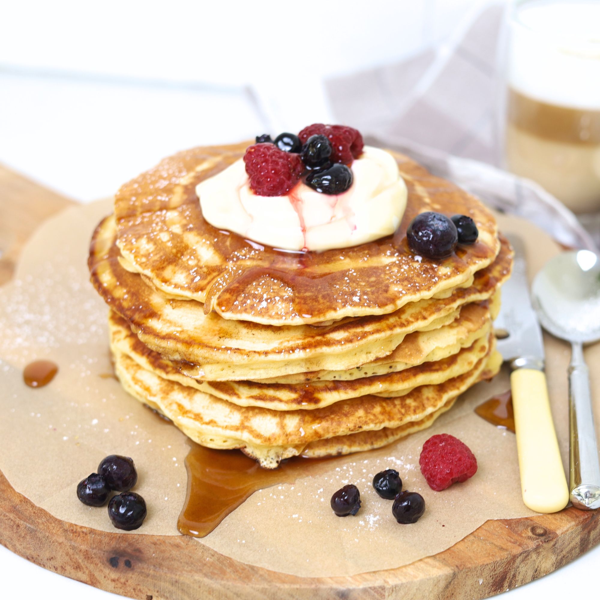 Plated breakfast of sourdough pancakes topped with whipped cream, blueberries, and raspberries.