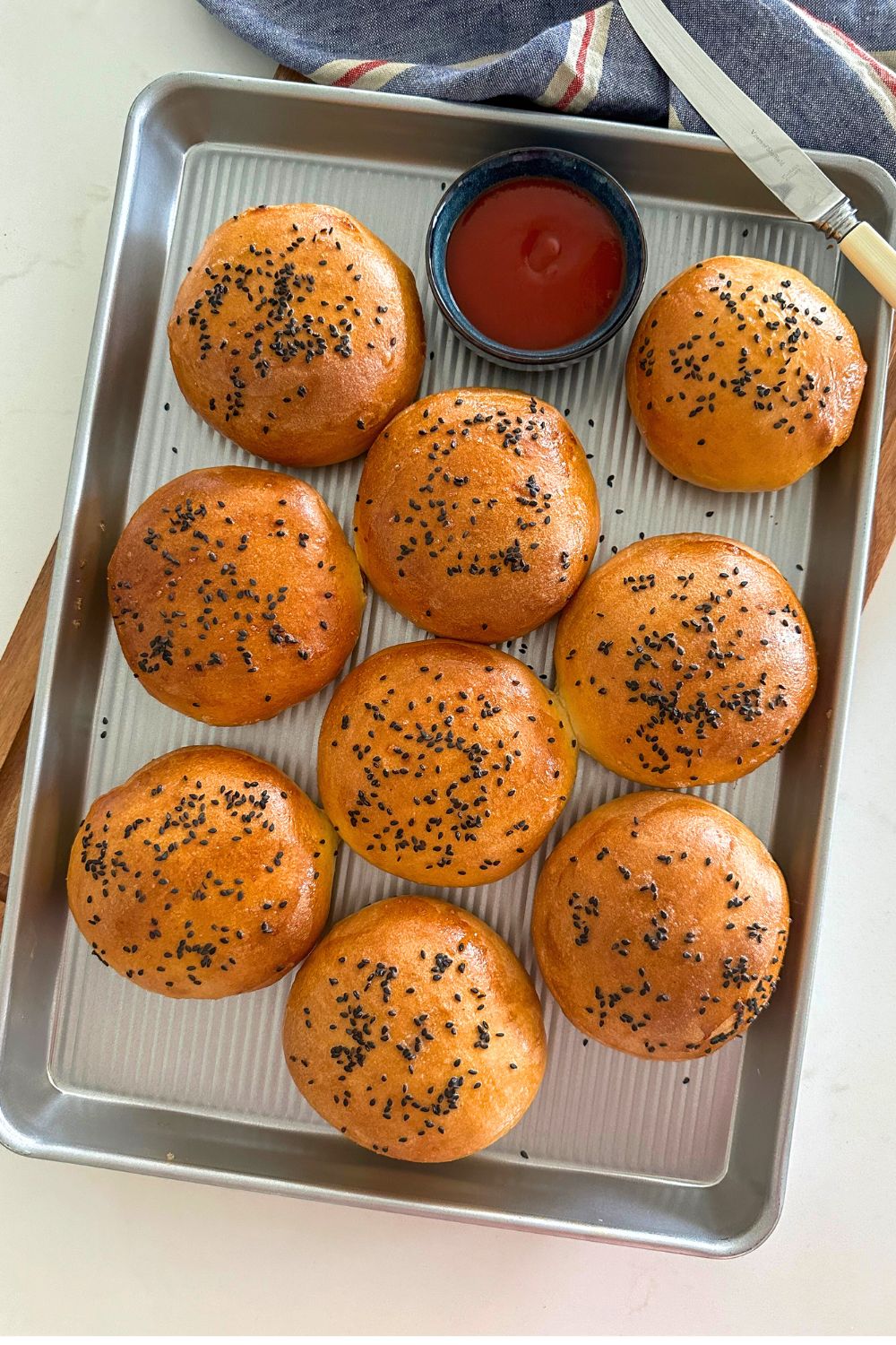 Nine sourdough poppy seed rolls on a baking sheet.