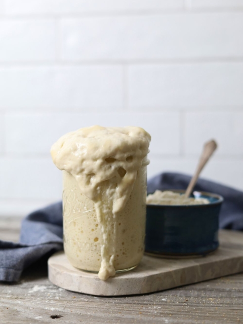 Jar of sourdough starter bubbling over the top of the jar.