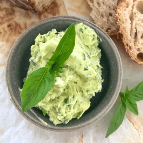 Small bowl of creamy green dip garnished with fresh basil.
